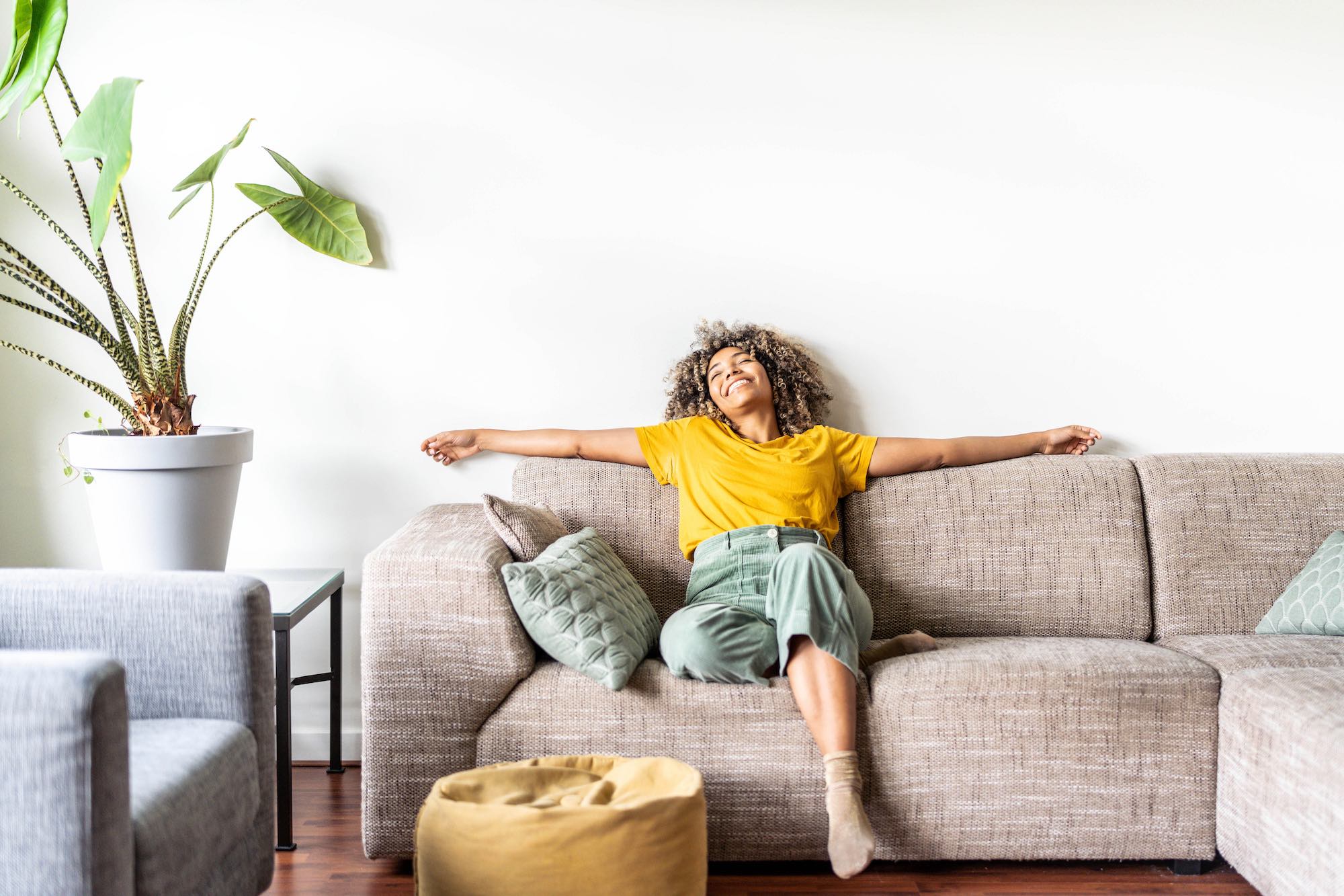 happy afro american woman relaxing on the sofa at home smiling girl enjoying day off lying on the couch healthy life style, good vibes people and new home concept